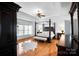 Luxurious main bedroom featuring a four-poster bed, hardwood floors, and natural light at 16532 Flintrock Falls Ln, Charlotte, NC 28278