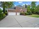 Three-car garage with brick exterior, large driveway, and basketball hoop, perfect for a growing Gathering at 16532 Flintrock Falls Ln, Charlotte, NC 28278