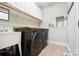 Laundry room featuring front load washer/dryer, utility sink, white cabinets, and modern lighting at 16532 Flintrock Falls Ln, Charlotte, NC 28278