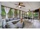 A sun room with large windows, a ceiling fan, a wicker couch and coffee table, and an outdoor dining set at 16532 Flintrock Falls Ln, Charlotte, NC 28278
