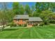 Classic brick home with a manicured lawn, mature trees, and black shutters on a sunny day at 2815 Burnt Mill Rd, Charlotte, NC 28210