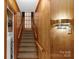 Carpeted staircase featuring wood-paneled walls and railings, illuminated by stylish wall sconces at 2815 Burnt Mill Rd, Charlotte, NC 28210