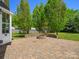 Inviting backyard with lush greenery, a stone patio, a built-in fire pit, and mature trees at 3002 Fair Meadows Dr, Monroe, NC 28110