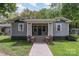 Charming home with a welcoming front porch, gray siding, and manicured lawn with a brick walkway and foundation at 303 S Iredell Ave, Spencer, NC 28159