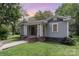 Charming home with a welcoming front porch, gray siding, and manicured lawn with a brick walkway and foundation at 303 S Iredell Ave, Spencer, NC 28159