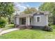 Charming home with a welcoming front porch, gray siding, and manicured lawn with a brick walkway and foundation at 303 S Iredell Ave, Spencer, NC 28159