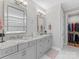 Bright bathroom featuring double vanity with granite counters, framed mirrors, and a walk-in closet with custom shelving at 4012 Moxie Way, Charlotte, NC 28215