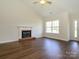 Cozy living room featuring wood floors, a brick fireplace with a mantle, and a large window at 4203 Ethel Sustar Dr, Monroe, NC 28110