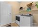 Well-organized laundry room featuring side-by-side washer and dryer, white shelving, and access door to outside at 536 Wellbourne Nw Ct, Concord, NC 28027