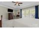 Bright main bedroom with tray ceiling, ceiling fan, and sunny window view at 536 Wellbourne Nw Ct, Concord, NC 28027