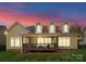 Exterior back view of home with covered deck and backyard space at dusk offering outdoor enjoyment at 541 Nw Sutro Forest Dr, Concord, NC 28027