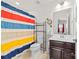 Bright bathroom featuring a vanity, toilet, and shower-tub combination with vibrant striped curtain at 6702 Carradale Way, Charlotte, NC 28278