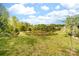 A tranquil pond with a natural stone edge is nestled in a lush green field surrounded by trees at 6702 Carradale Way, Charlotte, NC 28278