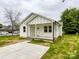 A cozy single-story home with a welcoming front porch and a concrete driveway on a cloudy day at 712 N Washington St, Shelby, NC 28150