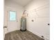A modern laundry room with white walls, hardwood floors, a water heater and wire rack shelving at 712 N Washington St, Shelby, NC 28150