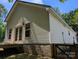 Angle view of the home's light siding, foundation, and French doors leading to a deck under a clear, blue sky at 8332 Highlander Ct, Charlotte, NC 28269