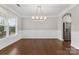 Open dining room with wainscoting, hardwood floors, and a modern chandelier at 9303 Raven Top Dr, Mint Hill, NC 28227