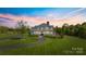 Gorgeous home with a wrap-around porch, mature trees, and a long winding driveway at sunset at 1065 Hunter Bridge Rd, Stony Point, NC 28678