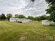 Wide shot of fenced yard with well-maintained lawn, mature trees and several buildings and utility sheds at 109 Georgia Belle Ave # 199, Belmont, NC 28012