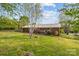 Green backyard view featuring the rear of a brick house, partial fence, and ample space for outdoor activities at 1195 Ralph B Keener Rd, Lincolnton, NC 28092