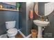 Stylish powder room with a pedestal sink, a round mirror, and dark blue walls at 13015 Rothe House Rd, Charlotte, NC 28273