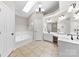 Bathroom with a tub, dual sinks, modern fixtures, and a skylight for natural lighting at 13324 Kintyre Ct, Matthews, NC 28105