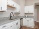 Well-lit kitchen featuring white cabinets, granite countertops, stainless steel sink, and a sleek black faucet at 13324 Kintyre Ct, Matthews, NC 28105