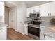 Bright kitchen with white cabinets, granite countertops, stainless steel appliances, and a modern oven range at 13324 Kintyre Ct, Matthews, NC 28105