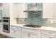 A modern kitchen features stainless steel appliances, white cabinets and a glass tile backsplash at 19006 Brandon James Dr, Cornelius, NC 28031
