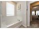 Relaxing bathroom featuring a soaking tub and window for natural light with neutral-colored tiles at 3100 Cheyney Park Dr, Charlotte, NC 28269