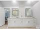 Bright bathroom boasts double vanity with white cabinets and modern, lighted mirrors at 3201 Oak Brook Dr, Waxhaw, NC 28173