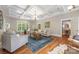 Open-concept living room featuring hardwood floors, coffered ceilings, neutral furniture, and many windows for natural light at 3201 Oak Brook Dr, Waxhaw, NC 28173