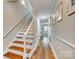 Bright hallway with hardwood floors, staircase and decorative wainscoting leading to a naturally lit area at 4607 Hedgemore Dr # H, Charlotte, NC 28209