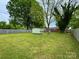 Large backyard with a storage shed and mature trees, surrounded by a wooden fence at 4623 Monmouth Dr, Charlotte, NC 28269