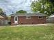 Brick house featuring a door to a backyard with green grass and a concrete patio at 4623 Monmouth Dr, Charlotte, NC 28269