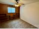 This bedroom features carpet, wood paneled walls, a ceiling fan and built in bookshelves at 4623 Monmouth Dr, Charlotte, NC 28269
