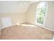 Sunlit bedroom with neutral walls and carpet features an arched window and ceiling fan at 4704 Beech Crest Pl, Charlotte, NC 28269