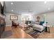 Open-concept living room featuring hardwood floors, a ceiling fan, and a cozy seating area with fireplace at 4931 Pine Ridge Rd, Charlotte, NC 28226