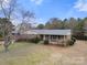 Aerial view of a brick home and front yard with mature trees, landscaping, and driveway offering curb appeal at 5303 Rogers Rd, Monroe, NC 28110