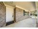 Charming brick front porch with a welcoming porch swing and white door at 5303 Rogers Rd, Monroe, NC 28110