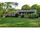 Charming brick home with a lush green lawn, blooming shrubs and mature trees offering curb appeal at 5303 Rogers Rd, Monroe, NC 28110