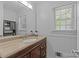 Classic bathroom with a wood vanity, neutral stone countertops, and natural light from the window at 6035 Idlebrook Dr, Charlotte, NC 28212