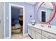 Stylish bathroom with blue walls, a large round mirror, and a glimpse into an adjacent bedroom at 729 Lochaven Rd, Waxhaw, NC 28173