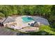 Aerial view of a community pool featuring lounge chairs, splash pad, and a clubhouse surrounded by mature trees at 7815 Scottsburg Ct, Mint Hill, NC 28227