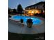 An in-ground pool is illuminated at twilight behind the home's covered patio at 8014 Avanti Dr, Marvin, NC 28173