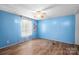 Bright bedroom featuring blue walls, wood-look floors, ceiling fan and natural light at 8705 Carroll St, Hickory, NC 28601