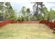 An open backyard area featuring a red wooden fence on a sunny day at 8820 First Run Ct, Charlotte, NC 28215