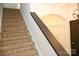 Carpeted stairs with wooden handrail and a decorative light fixture leading to the upper level at 8820 First Run Ct, Charlotte, NC 28215