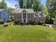 Two-story brick home featuring a red door, landscaped front yard and lush green trees at 9000 Stourbridge Dr, Huntersville, NC 28078
