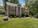 Two-story brick home featuring a red door, landscaped front yard and lush green trees at 9000 Stourbridge Dr, Huntersville, NC 28078